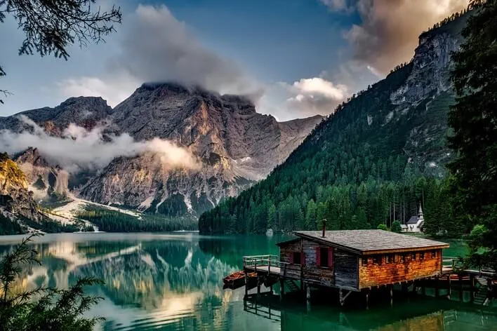 Cottage on a lake surrounded by mountains.